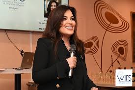 WIFS Los Angeles speaker on stage with handheld mic in front of branded backdrop