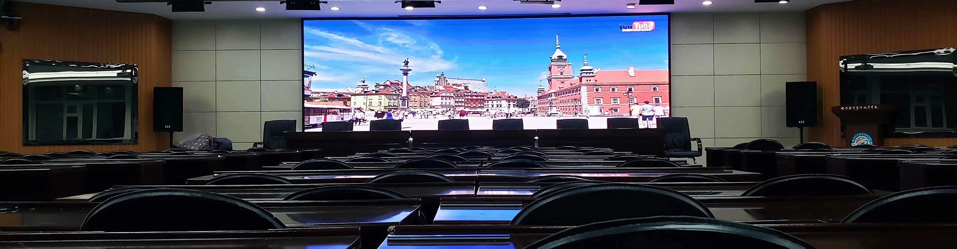 Indoor auditorium with large fine-pitch LED video wall displaying a cityscape